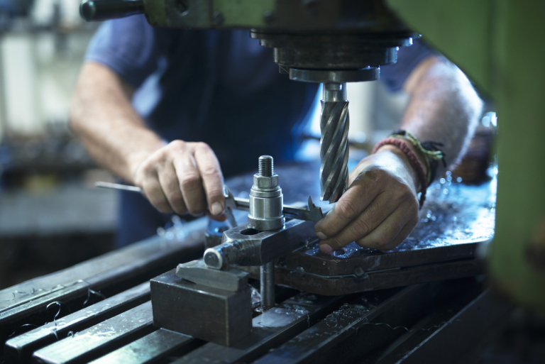 Worker operating industrial machine in metal workshop.